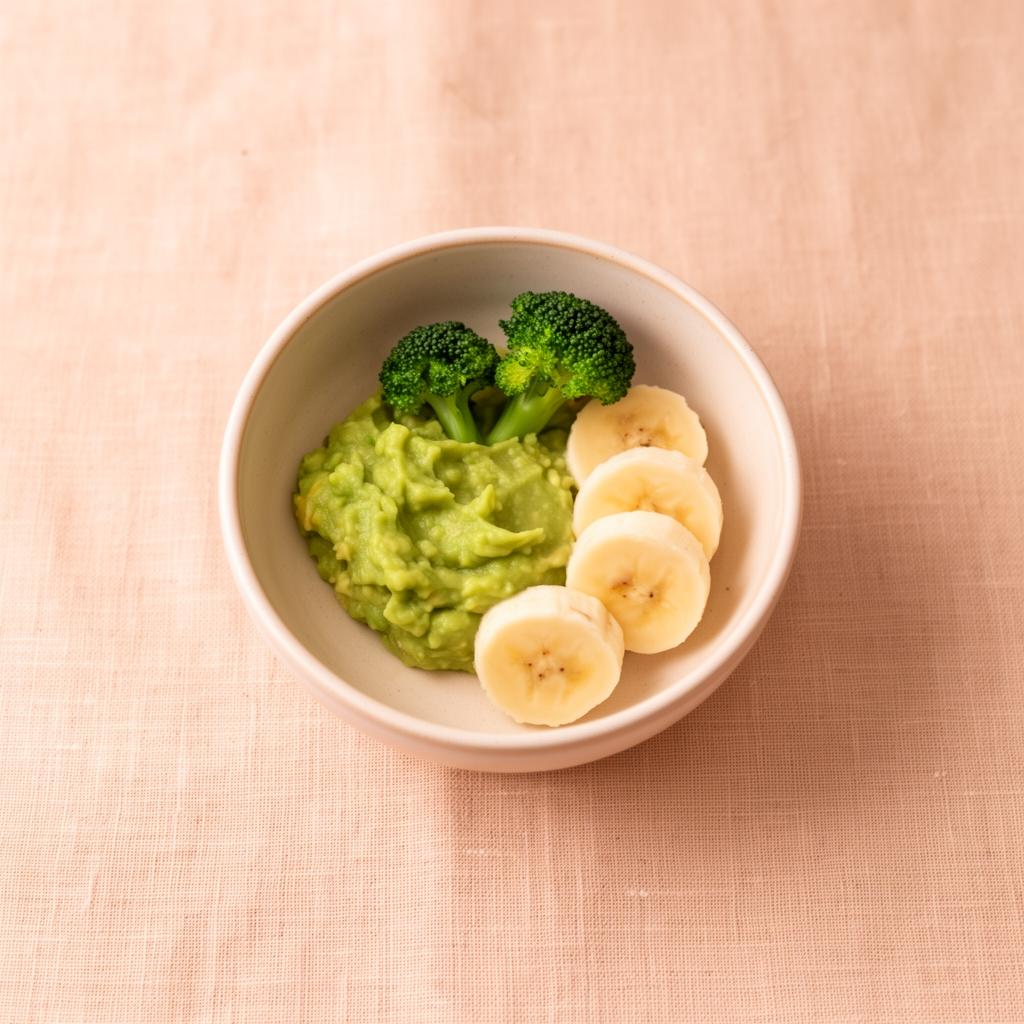 Liten skål med mosad avokado, broccoli och bananskivor